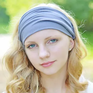 Close-up detail of the wide grey elastic yoga headband worn by a model outdoors.