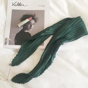 Dark green pleated silk scarf detail shot, showing delicate texture and elegant folds for decor.