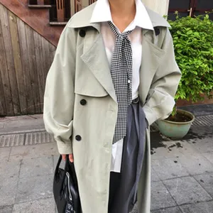 Detailaufnahme eines klassischen langen Trenchcoats mit weißem Hemd und kariertem Halstuch.