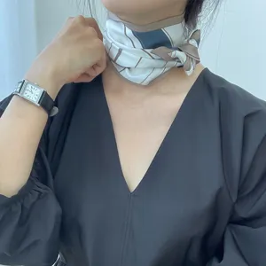 Détail de foulard en soie à motif rayé élégant porté autour du cou pour tenues stylées.