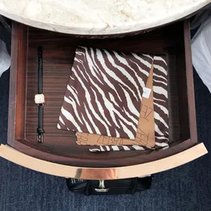 Detailansicht eines stilvollen Seidenschals mit Tiermuster und Uhr in einer Holzlade.