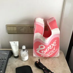 Rosa weiße gestrickte Handtasche Detailansicht, lässige Stricktasche mit süßem Herzmuster.