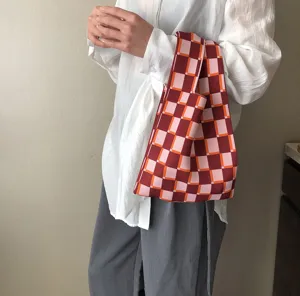 Nahaufnahme einer stilvollen dreifarbigen karierten Strickhandtasche mit feiner Textur.