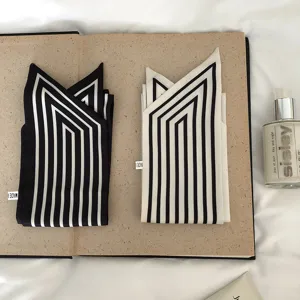 Detailansicht von schwarz-weißen gestreiften schmalen Seidenschals, elegante Flatlay-Stilisierung.