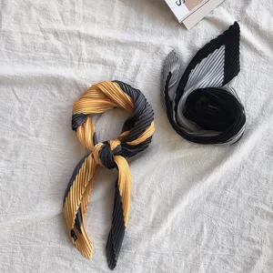 Detailed closeup of chic pleated square scarf and hair band, stylish neck accessory.
