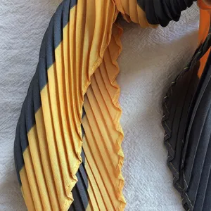 Close-up view showing the exquisite pleated texture and chic pattern of the black-yellow scarf.