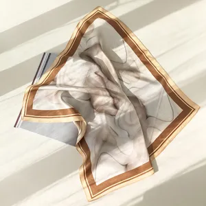 Close-up of milk tea color silk scarf with abstract sand painting print and brown border.