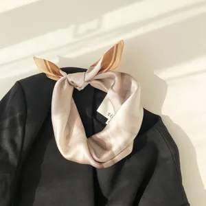 Detailed close-up view of a luxurious milk tea color silk small square scarf tied neatly.