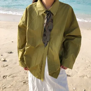Vue détaillée du ruban foulard en soie florale verte associé à une chemise à la plage.