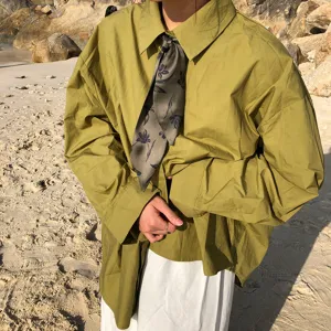 Vue rapprochée de la chemise oversize vert olive avec un élégant foulard en soie à fleurs.