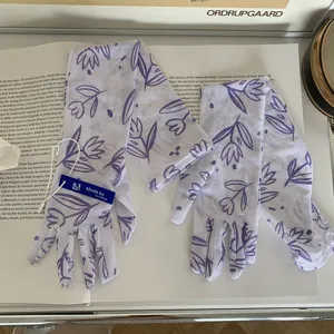Gros plan de gants longs de protection solaire en maille blanche avec motifs floraux.