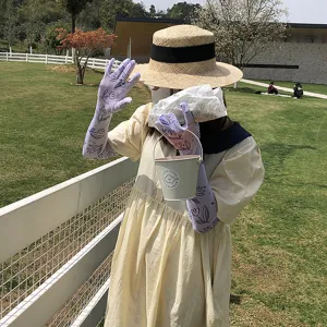 Détail de la scène extérieure montrant des manches de protection solaire florales violettes.