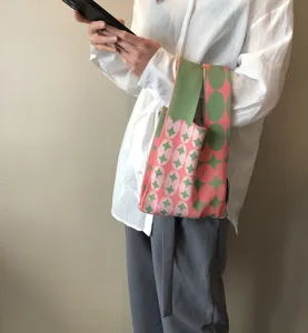 Nahaufnahme einer bunten Strickhandtasche mit geometrischen Punkten, tragbarer Freizeitstil.
