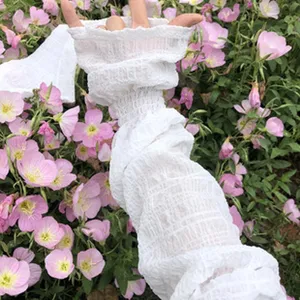 Detail view of white sun protection arm sleeves with ruffles, breathable fabric, ideal for summer.