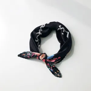 Detailed view of black pleated silk scarf with colorful floral ends, chic hair band accessory.