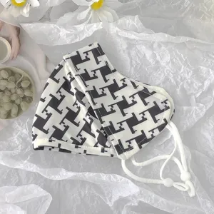 Close up detail of black and white geometric pattern sun protection face mask with adjustable strap.