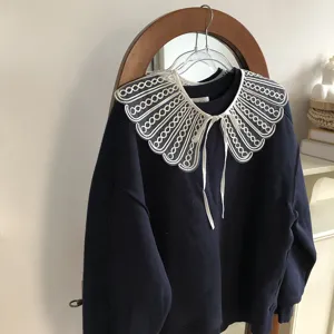 Detailed view showing dark blue sweatshirt with exquisite white embroidered lace detachable collar.
