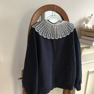 Detailed view of dark blue sweatshirt with white embroidered hollow-out lace fake collar