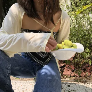 Εξωτερική λεπτομέρεια από ελαφριά λευκή ζακέτα αντηλιακής προστασίας με κομψό τοπ.