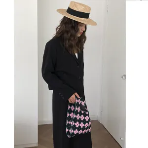 Detailaufnahme einer stilvollen schwarz-pinken Stricktasche mit Blumenmuster.