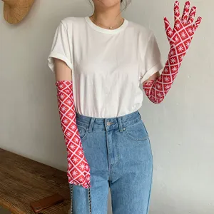 Detailansicht roter gemusterter Sonnenschutz-Ärmel, kombiniert mit weißem T-Shirt und Jeans.