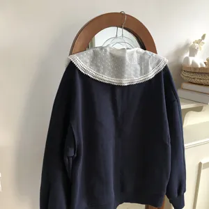 Detail shot of stylish lace doll collar matched with dark blue sweatshirt, chic fashion accessory.