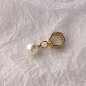 Nahaufnahme des Produktdetails mit einem goldenen Sechseckring und weißer Perle.