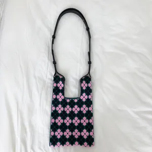 Detailansicht des rosa schwarzen gestrickten Blumenmusters und Schulterriemens der Tasche.