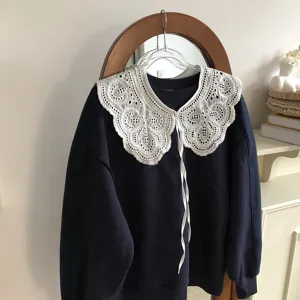 Close up of the detachable white hollow lace doll collar on a navy blue sweatshirt detail.
