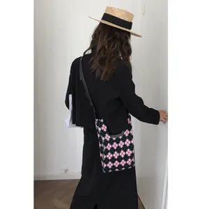 Detailaufnahme einer stilvollen gestrickten Umhängetasche mit schickem rosa Blumenmuster.