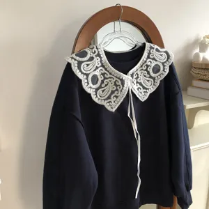 Close-up detail of navy sweatshirt showcasing intricate white lace embroidered collar.