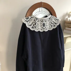 Versatile dark blue top paired with a delicate white hollow embroidered fake collar, stylish.