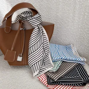 Close-up detail of smooth satin square scarf with geometric stripe pattern and styling bag.