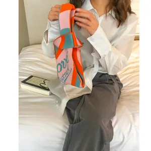 Bunte Strickhandtasche mit lebendigen Streifen und gewebtem Schriftzug. Trendige Freizeittasche.