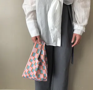 Detailaufnahme der bunten karierten Strickhandtasche mit modischem rosa blauem Design.