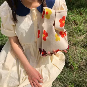 Nahaufnahme des gestrickten Blumen-Handgelenktaschendetails draußen auf Gras, weich.