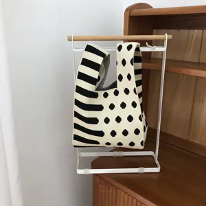 Schwarze und weiße Strickhandtasche mit einzigartigem Pünktchen- und Streifenmuster.
