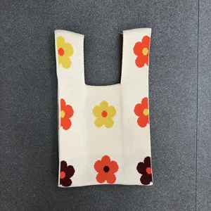 Detailaufnahme einer gestrickten Blumen-Handgelenktasche mit weicher Textur und bunten Mustern.