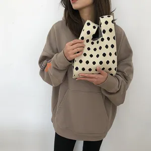 Detailaufnahme einer eleganten schwarz-weissen Polka-Dot Strick-Handtasche für den Frühling.