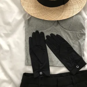 Detail view of black UV protection touchscreen gloves styled with a hat and casual summer outfit.