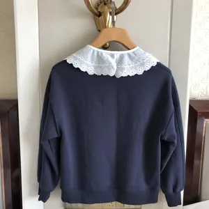 Detailansicht eines dunkelblauen Sweatshirts mit einem eleganten weißen Spitzenkragen.