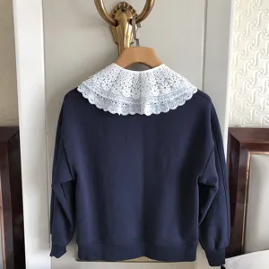 Detailansicht eines dunkelblauen Sweatshirts mit einem eleganten weißen Spitzkragen.