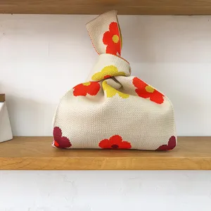 Strick Handgelenk Tasche Detail mit cremigem Beigefarbton und lebendigem rot gelben Blumenmuster.
