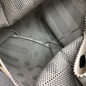 Nahaufnahme der Textur der schwarz-weißen Stricktasche, die feines Webmuster zeigt.