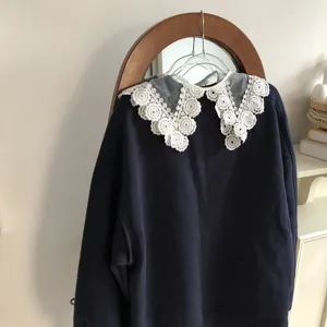 Detail shot of a dark blue sweatshirt featuring an exquisite white crochet lace detachable collar.