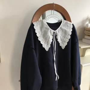 Detailed close-up of a elegant white hollow-out lace doll collar paired with dark blue top.