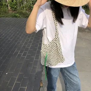 Schwarz-weiße Strick-Umhängetasche mit Punkten und grünem Riemen, lässiges Damen-Accessoire.