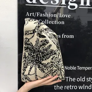 Schwarze weiße Strickhandtasche mit tropischem Palmenmuster und integriertem Tragegriff.