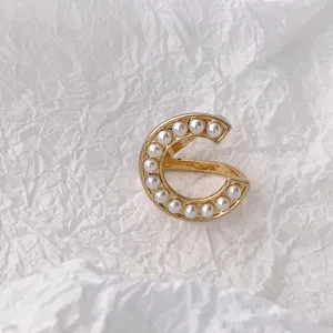 Detailaufnahme einer goldfarbenen C-förmigen Perlen-Schal Schnalle und Ring Zubehör.