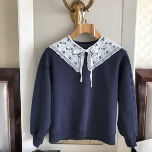 Nahaufnahmendetails des dunkelblauen Sweatshirts mit weißem Spitzenkragen und Schleife.